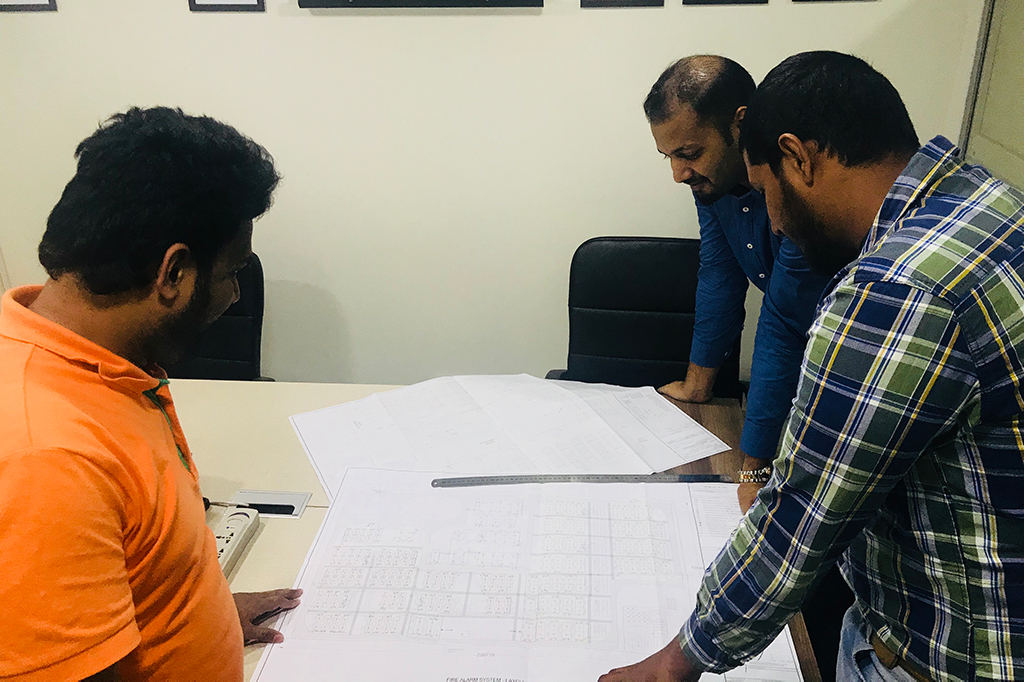 Three fire protection engineers reviewing technical blueprints